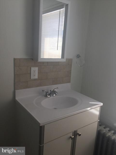 bathroom featuring vanity, radiator heating unit, and tasteful backsplash