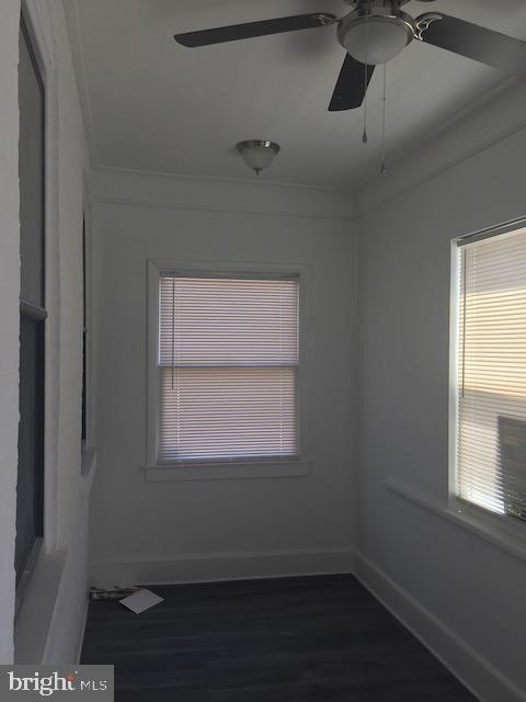 empty room featuring ornamental molding, dark hardwood / wood-style floors, and ceiling fan