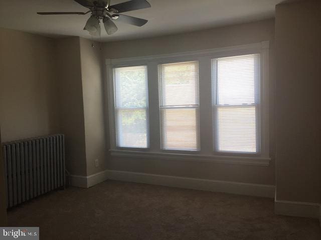 carpeted spare room featuring ceiling fan, plenty of natural light, and radiator