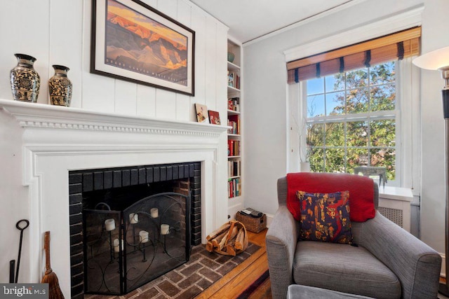 living area with a brick fireplace and hardwood / wood-style floors