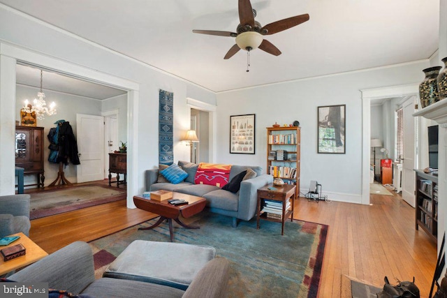 living room with ceiling fan with notable chandelier, wood-type flooring, and ornamental molding