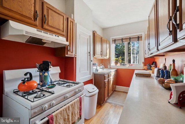 kitchen featuring sink, gas range gas stove, and light wood-type flooring