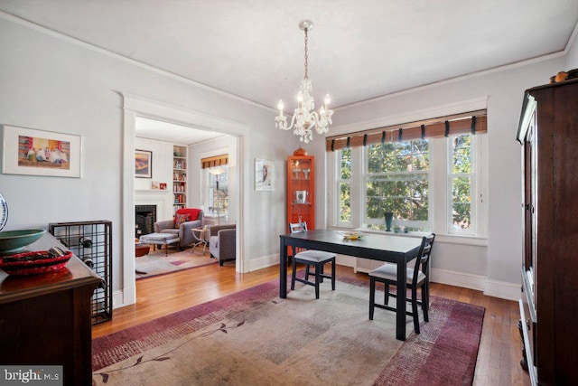 dining area featuring hardwood / wood-style floors, ornamental molding, built in features, and a chandelier