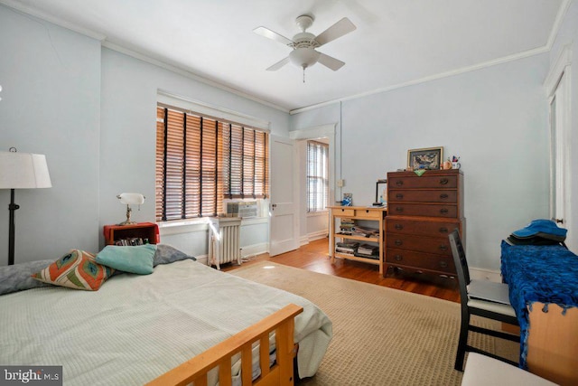 bedroom featuring crown molding, ceiling fan, radiator, and hardwood / wood-style floors