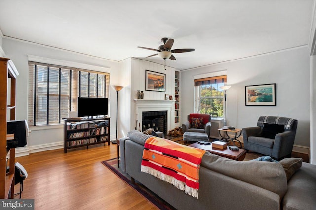 living room with wood-type flooring, built in features, and ceiling fan