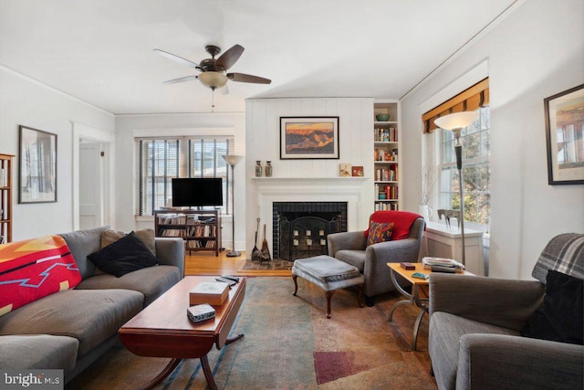 living room with ceiling fan, a healthy amount of sunlight, a fireplace, and built in shelves