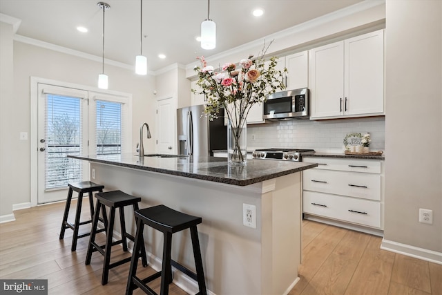 kitchen featuring appliances with stainless steel finishes, a kitchen island with sink, and white cabinets