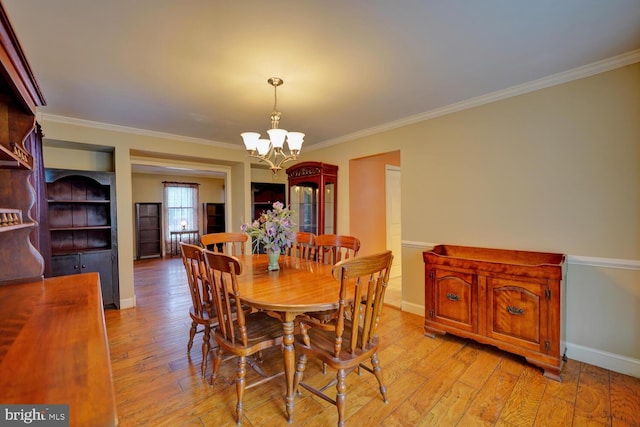 dining area featuring an inviting chandelier, crown molding, and light wood-type flooring