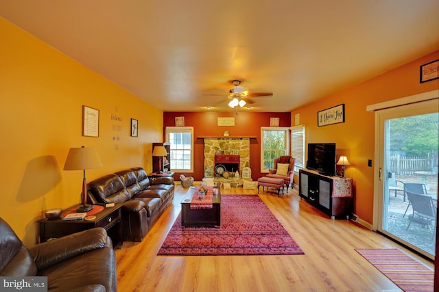 living room with ceiling fan, a fireplace, and light hardwood / wood-style flooring