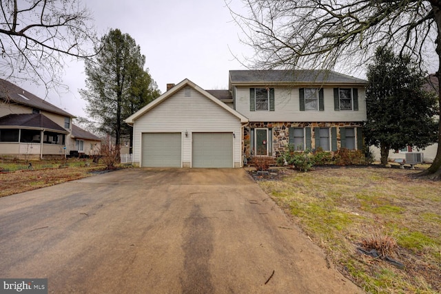 view of front facade with cooling unit, a garage, and a front lawn