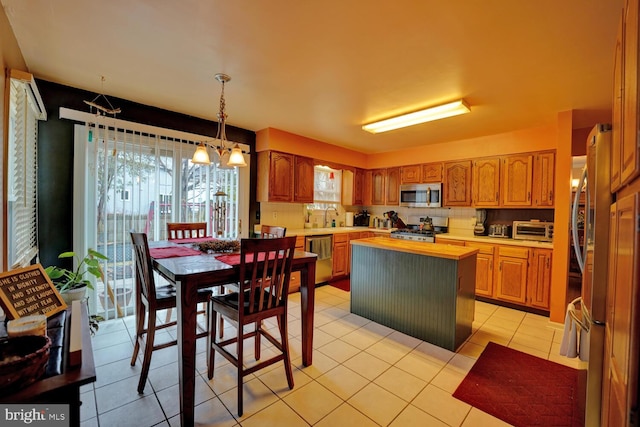 kitchen featuring sink, an inviting chandelier, stainless steel appliances, a center island, and tasteful backsplash