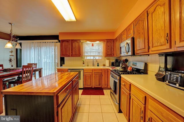 kitchen with sink, wooden counters, a center island, light tile patterned floors, and stainless steel appliances