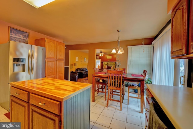 kitchen with butcher block countertops, stainless steel fridge, hanging light fixtures, a kitchen island, and light tile patterned flooring