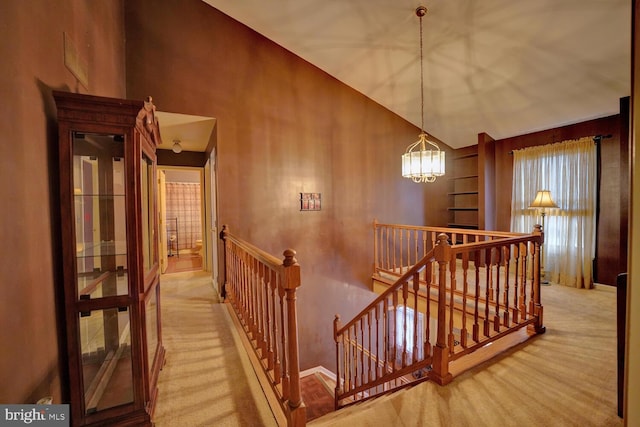 hallway featuring carpet flooring, a chandelier, and high vaulted ceiling