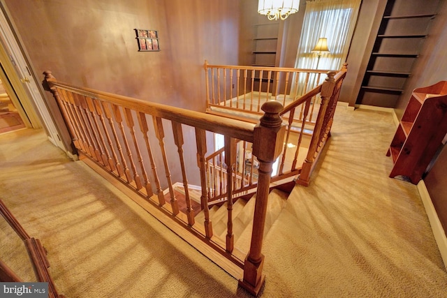 stairway with carpet floors and a notable chandelier