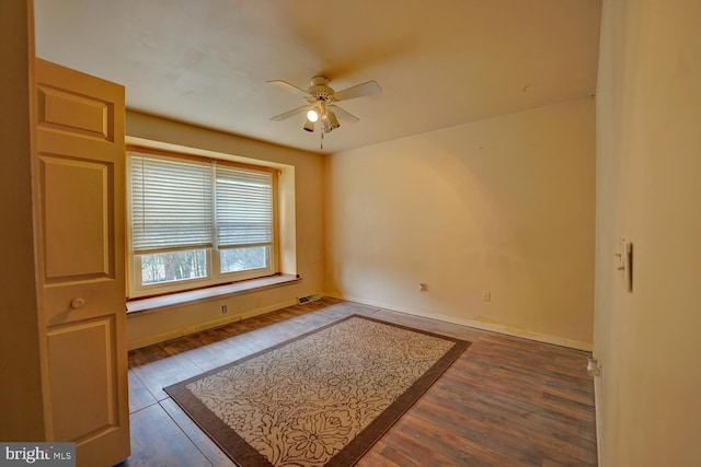 empty room with ceiling fan and dark hardwood / wood-style flooring