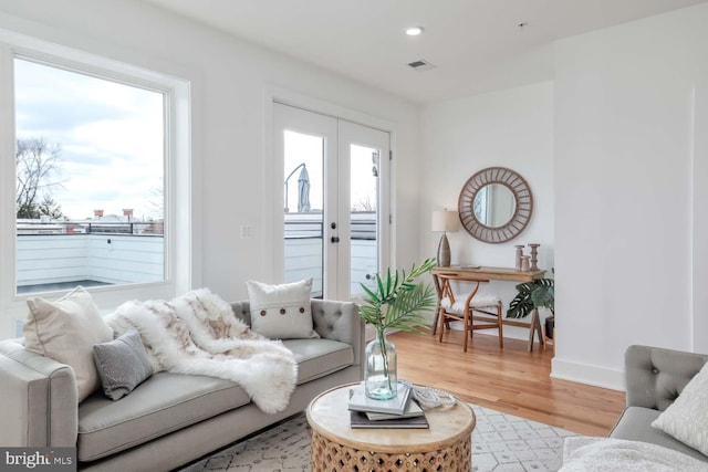 living room with french doors, plenty of natural light, wood finished floors, and visible vents