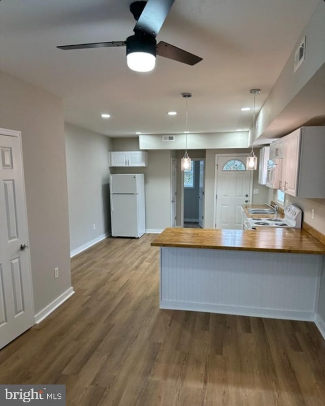 kitchen featuring pendant lighting, white appliances, hardwood / wood-style flooring, white cabinets, and kitchen peninsula