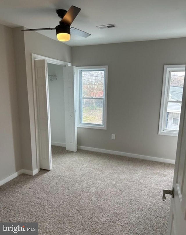 unfurnished bedroom featuring ceiling fan, light colored carpet, a closet, and multiple windows