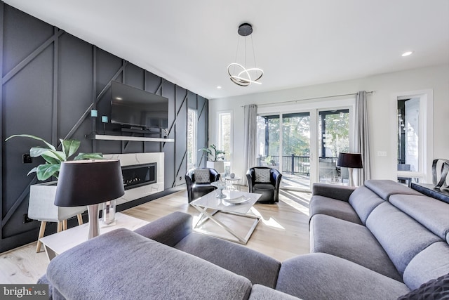 living room featuring a fireplace, light hardwood / wood-style floors, and a chandelier