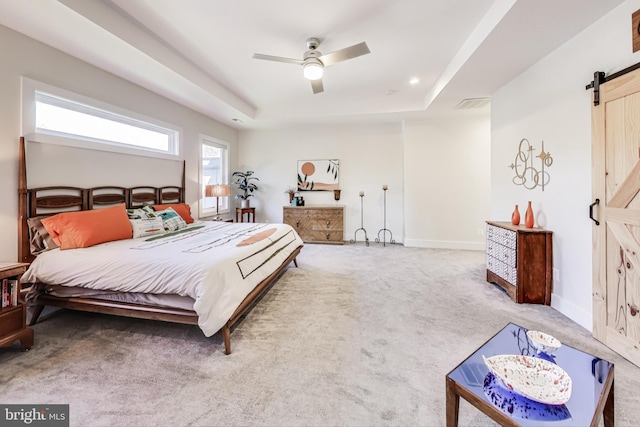 bedroom with a tray ceiling, a barn door, ceiling fan, and carpet