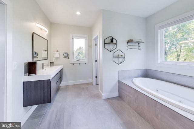 bathroom featuring tiled tub, vanity, plenty of natural light, and tile patterned flooring