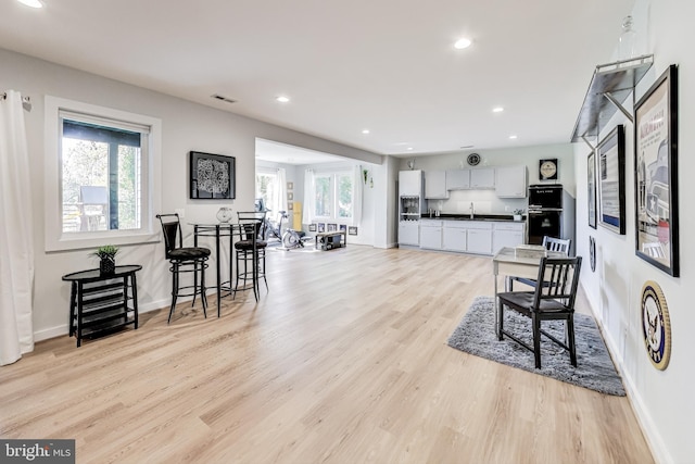 kitchen with white cabinetry, sink, a wealth of natural light, and light wood-type flooring