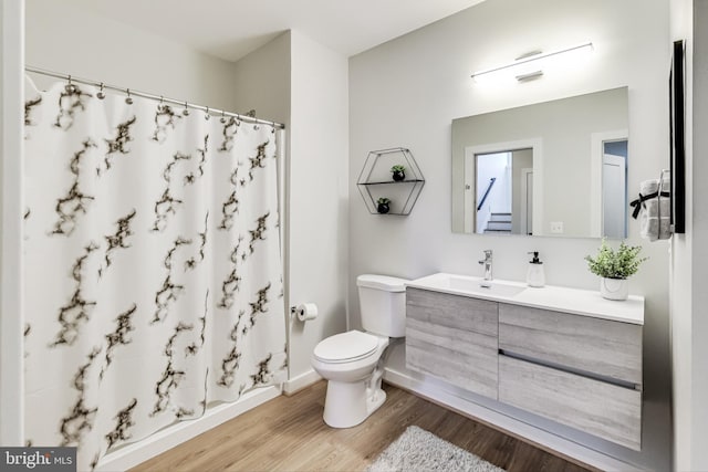 bathroom with wood-type flooring, curtained shower, vanity, and toilet