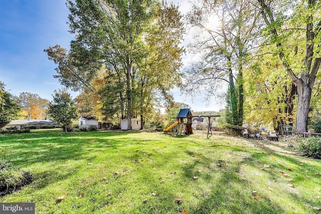 view of yard with a storage shed and a playground