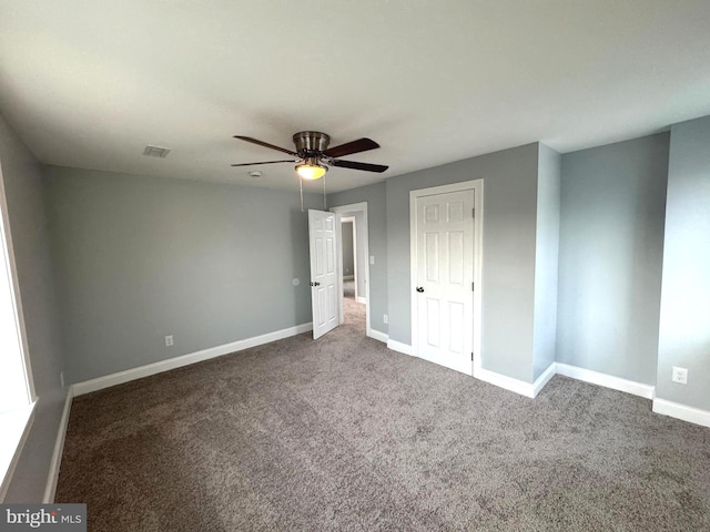 unfurnished bedroom featuring ceiling fan, a closet, and dark colored carpet