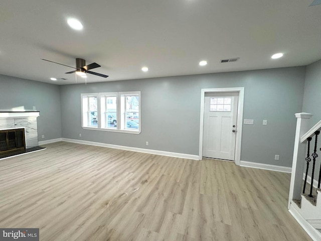 unfurnished living room with ceiling fan, a fireplace, and light hardwood / wood-style flooring