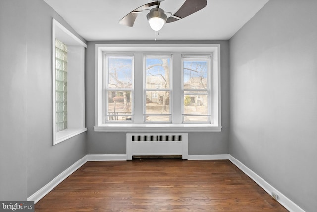 spare room featuring ceiling fan, dark hardwood / wood-style flooring, and radiator