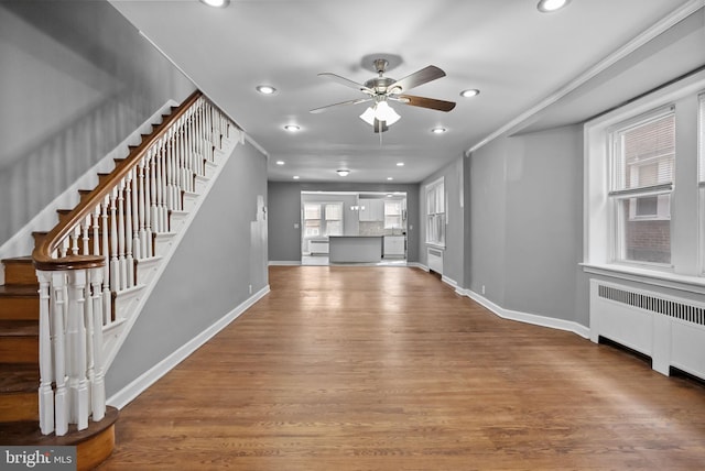 unfurnished living room featuring ceiling fan, wood-type flooring, and radiator