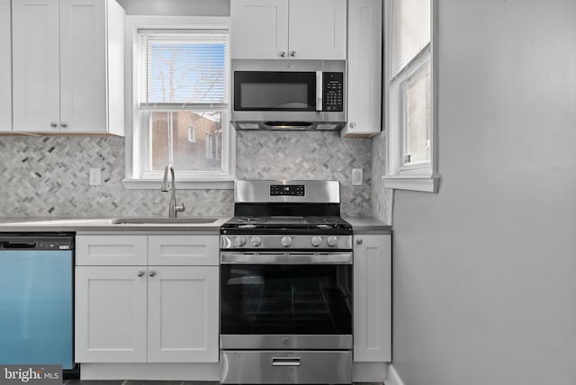 kitchen with stainless steel appliances, plenty of natural light, sink, and white cabinets