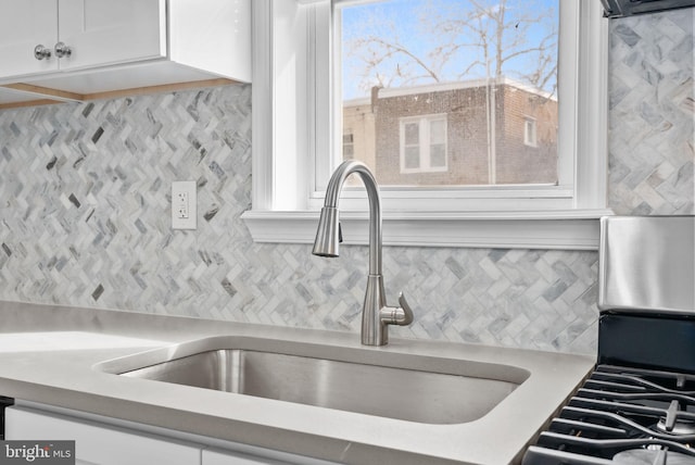 interior details with sink, backsplash, and white cabinets