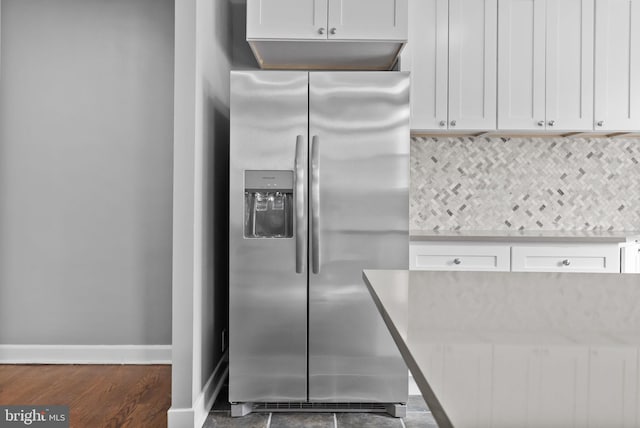 kitchen featuring stainless steel refrigerator with ice dispenser, white cabinetry, and backsplash