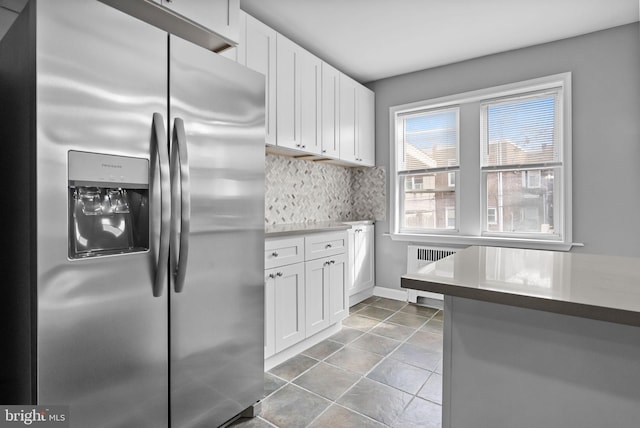 kitchen with radiator heating unit, stainless steel fridge with ice dispenser, decorative backsplash, and white cabinets