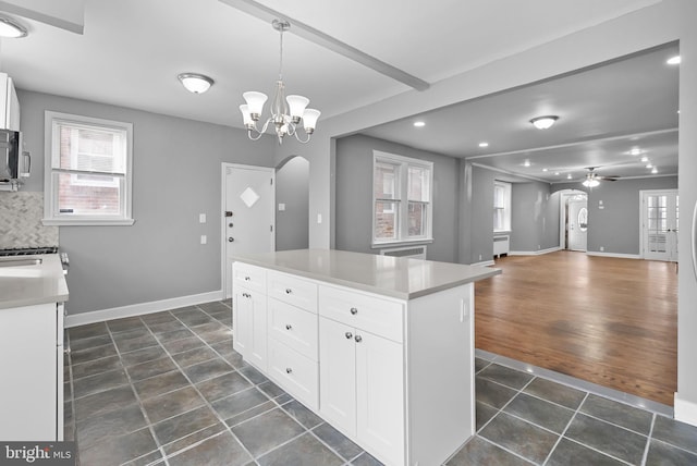 kitchen featuring white cabinetry, a center island, pendant lighting, ceiling fan with notable chandelier, and decorative backsplash