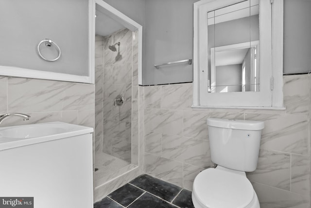 bathroom featuring vanity, toilet, tile walls, and a tile shower