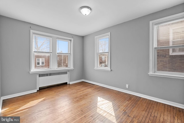 unfurnished room featuring radiator and light hardwood / wood-style flooring