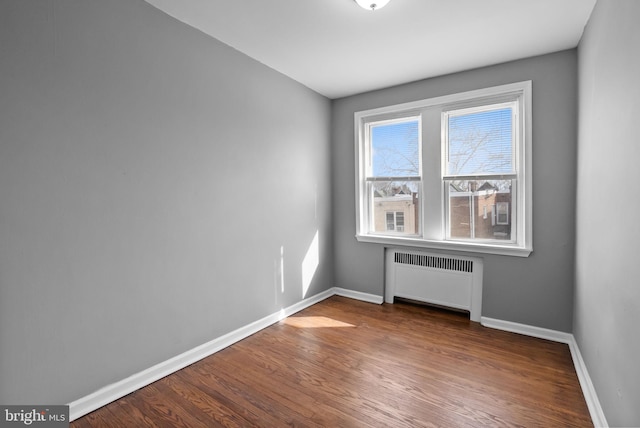 empty room with radiator and hardwood / wood-style floors