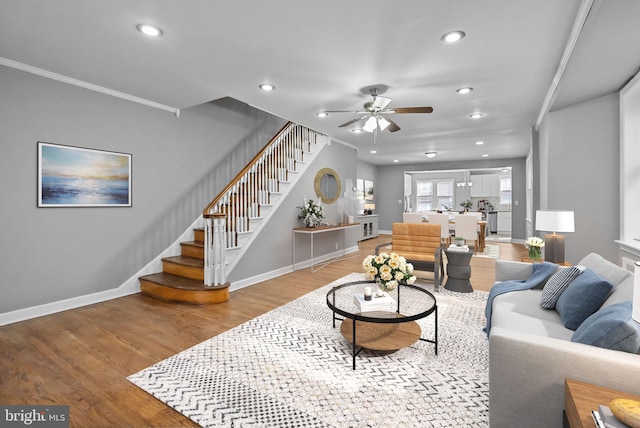 living room with wood-type flooring, ornamental molding, and ceiling fan