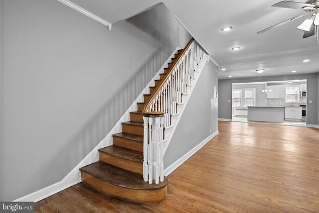 stairs with wood-type flooring and ceiling fan