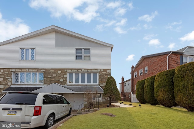 rear view of property featuring a garage and a lawn