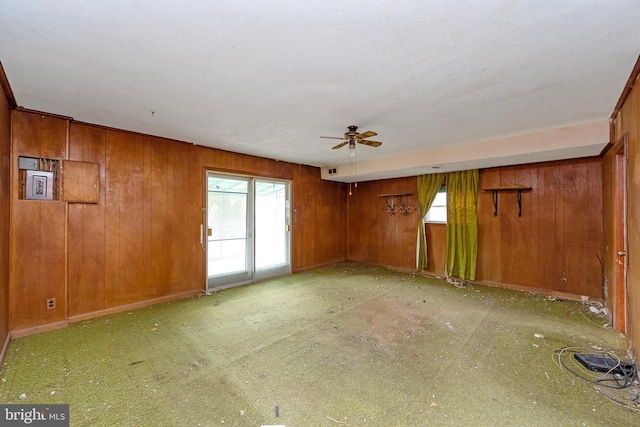 empty room featuring ceiling fan and wood walls