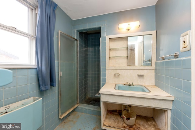 bathroom featuring tile patterned flooring, sink, tile walls, and a shower with shower door