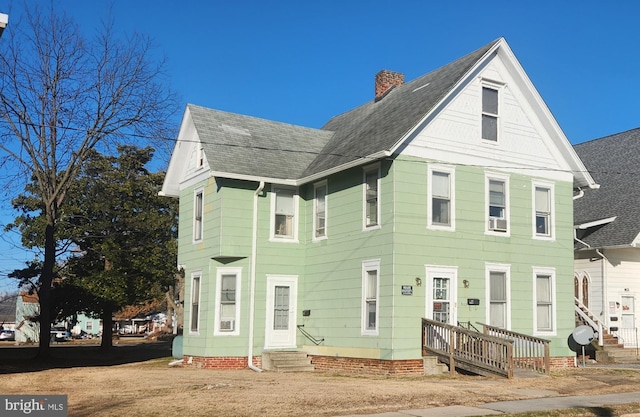 view of front of home featuring entry steps, roof with shingles, and a chimney