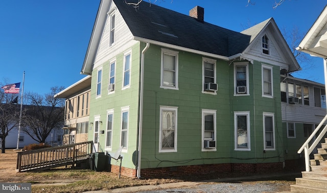 view of side of home featuring a shingled roof, a chimney, and cooling unit