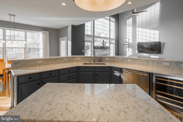 kitchen featuring sink, dishwasher, wine cooler, light stone countertops, and decorative light fixtures