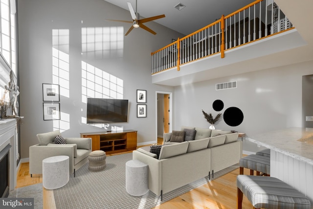 living room featuring a towering ceiling, light hardwood / wood-style flooring, and ceiling fan